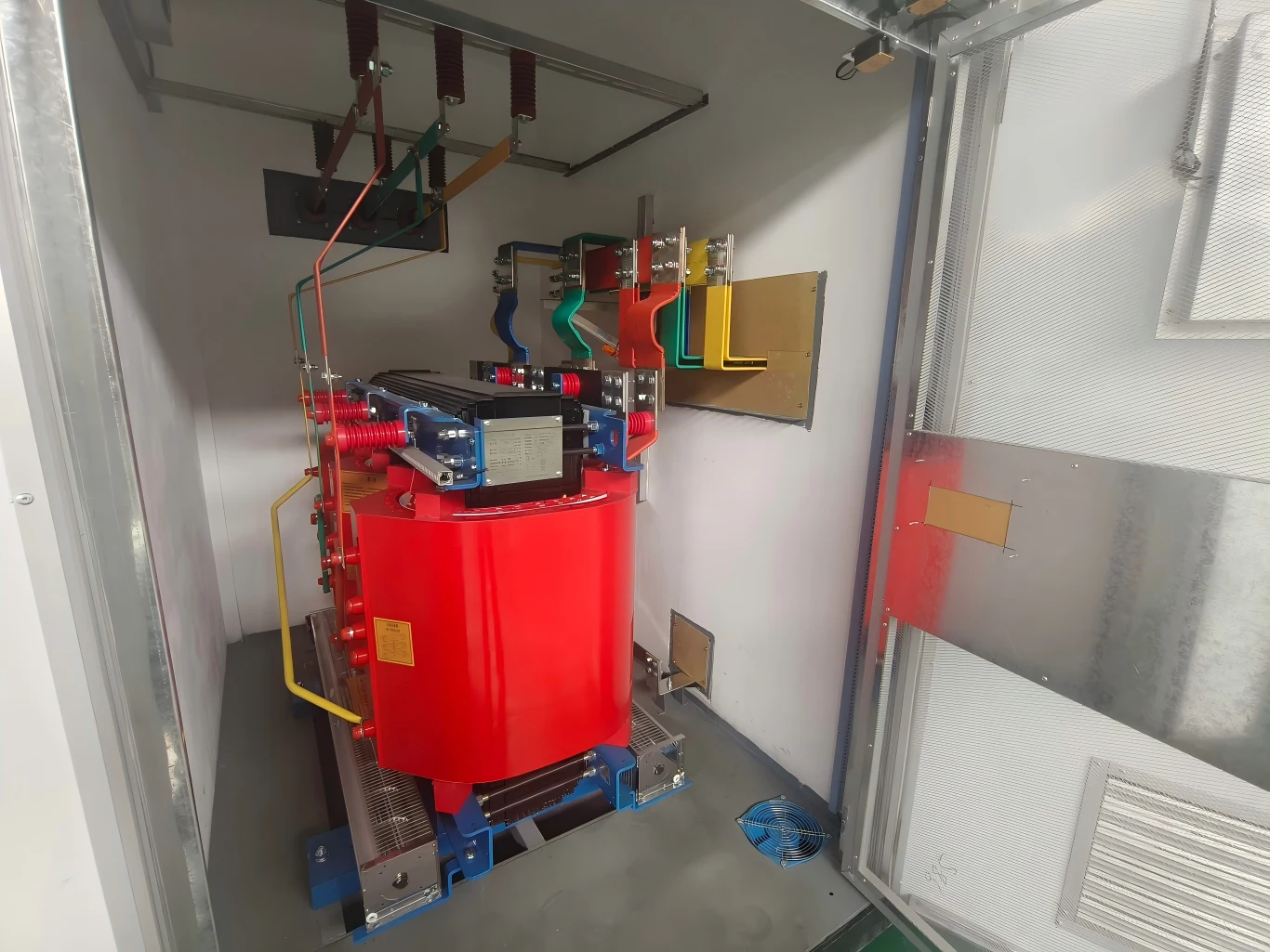 Cast resin dry-type transformer installed on rails with cooling fans inside a compact substation enclosure