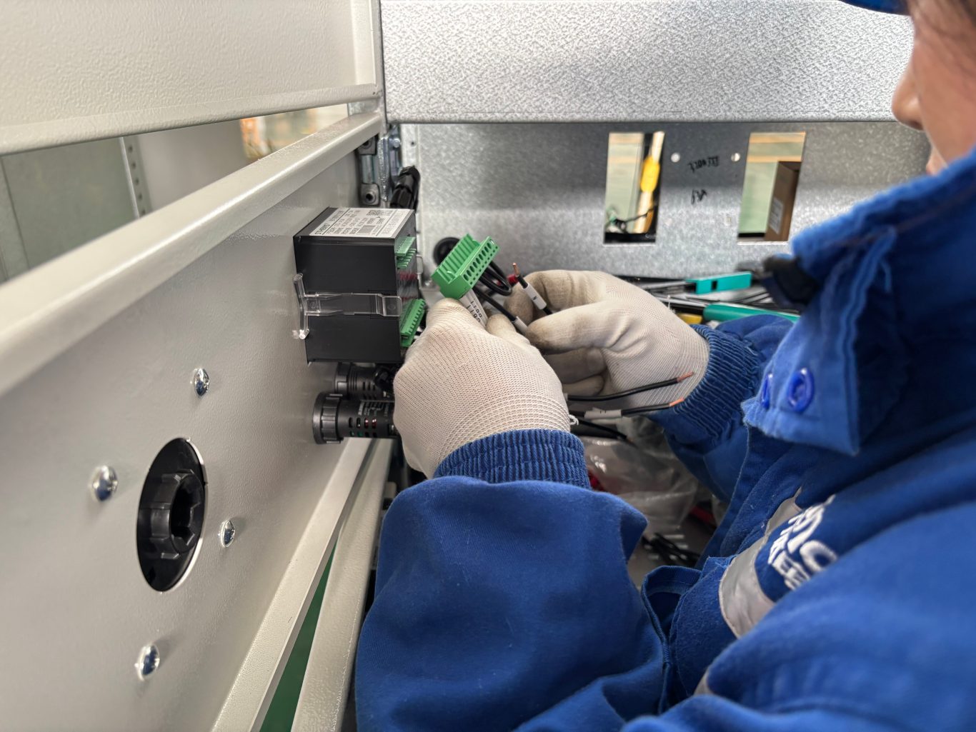 Electrician wiring control terminals inside low voltage switchgear cabinet