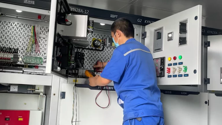 Engineer performing secondary wiring and testing on a KYN28A-12 medium voltage switchgear panel with a multimeter
