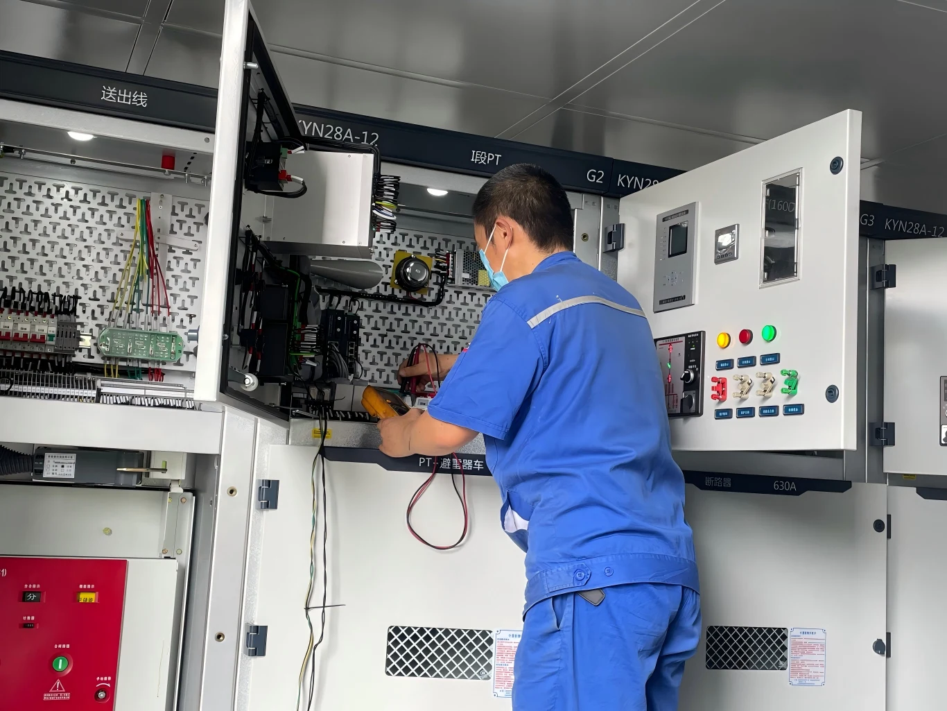 Engineer performing secondary wiring and testing on a KYN28A-12 medium voltage switchgear panel with a multimeter
