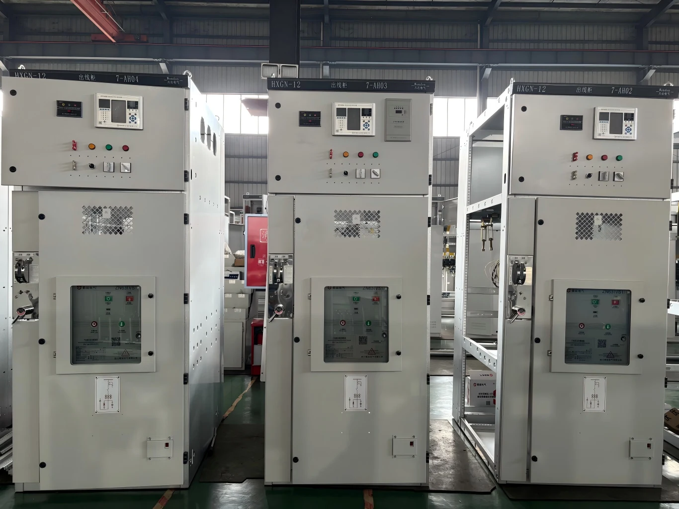 Rows of metal enclosed switchgear panels with control displays and indicator lights in a factory workshop