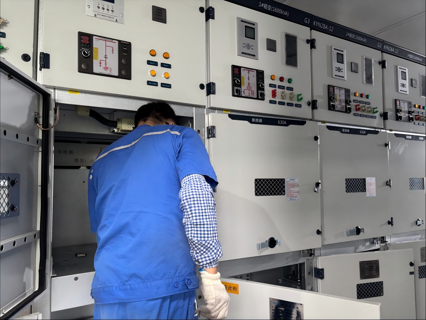 Technician inspects internal wiring of KYN28A-12 10kV medium voltage switchgear inside prefabricated substation cabint