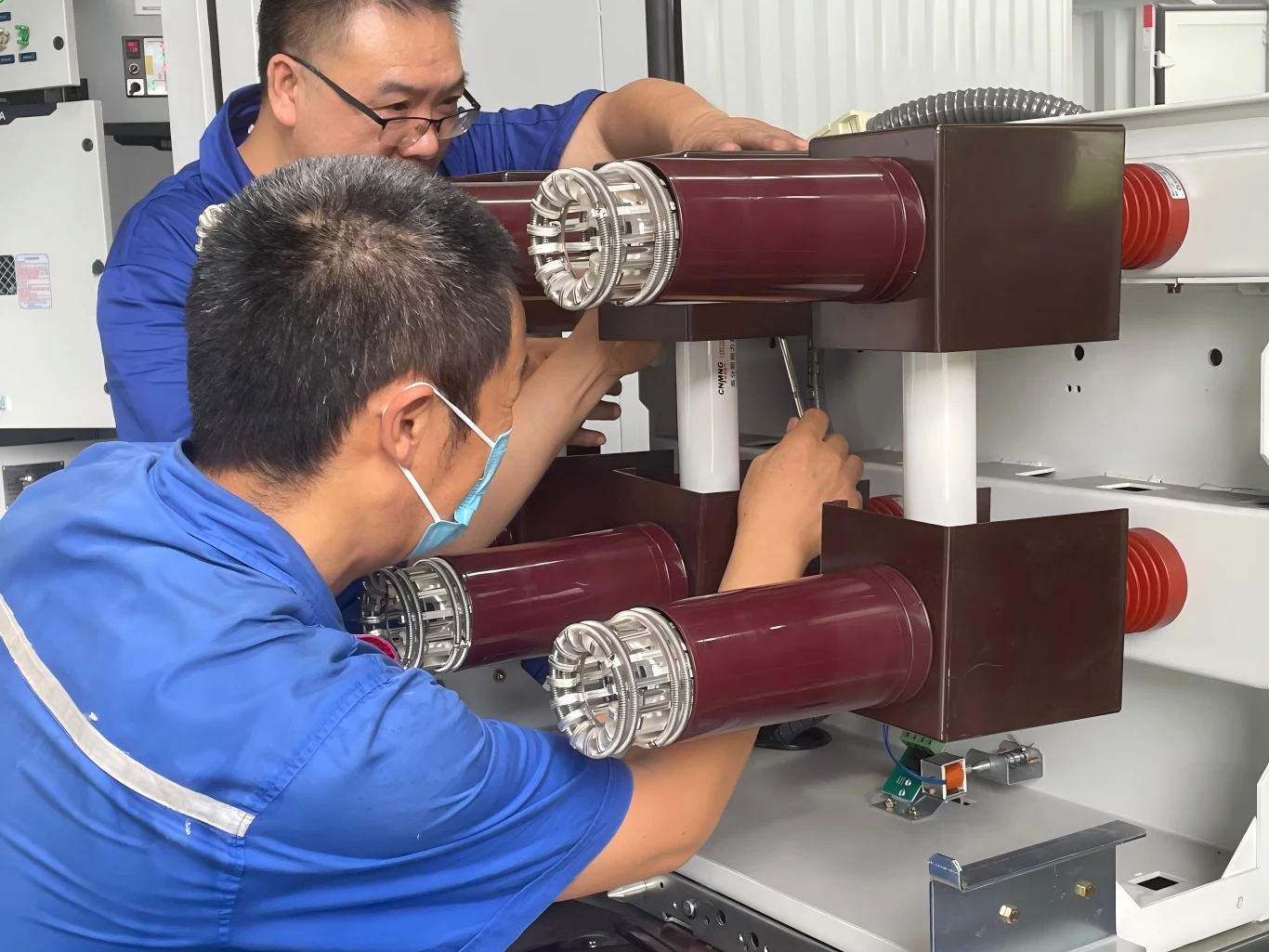 Technicians installing vacuum circuit breaker poles inside a medium voltage switchgear cubicle during assembly