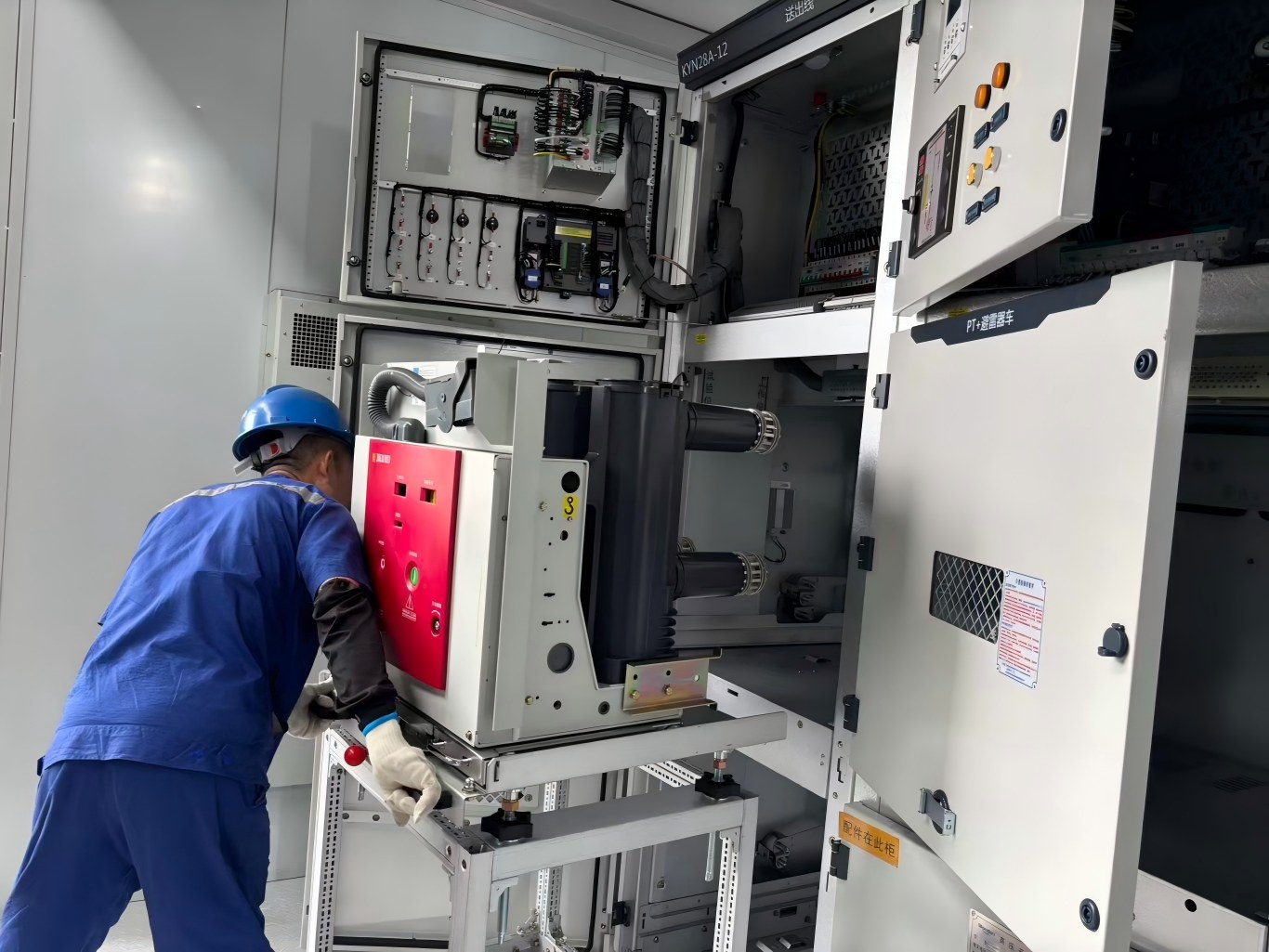 Worker inserts vacuum circuit breaker trolley into medium voltage switchgear