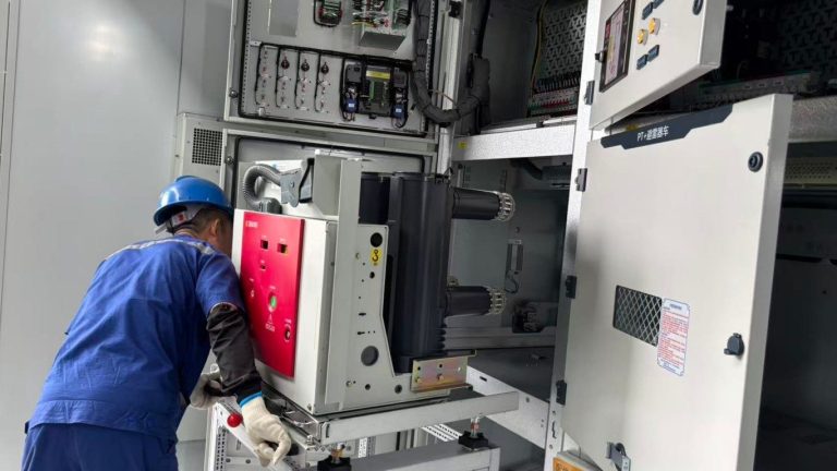 Workers install vacuum circuit breakers in medium voltage switchgear KYN28A-12