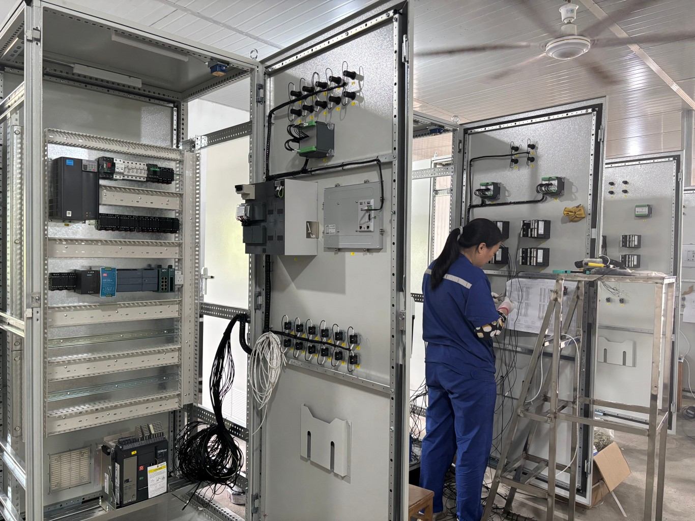 Technician wiring industrial control cabinet according to schematic diagram